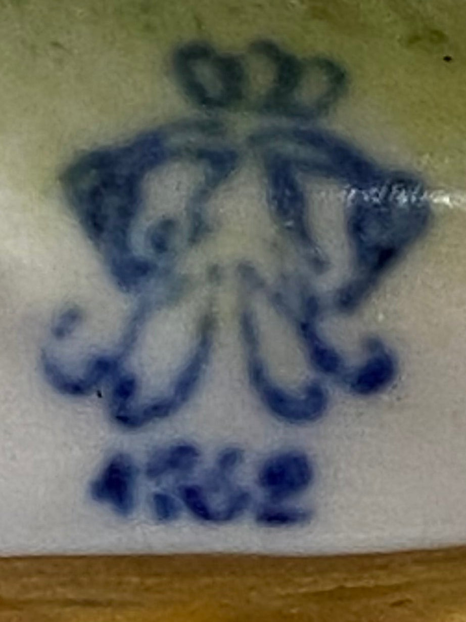 Close-up of a decorative item with gold frame and blue floral design on a textured surface
